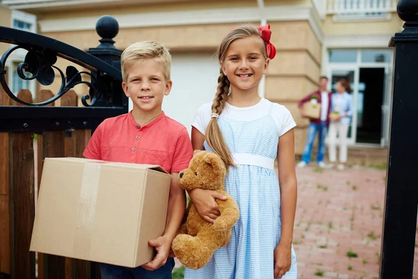 Hermana y hermano ayudando a llevar las cosas — Foto de Stock