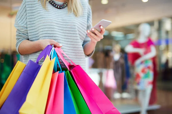 Shopper with paper bags using smartphone — Stock Photo, Image