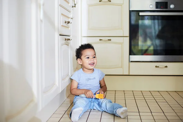 Kind zit op de keukenvloer — Stockfoto
