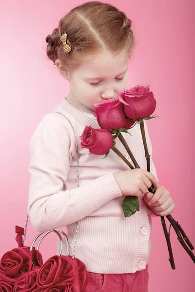 Маленька дівчинка з трояндами і рожевою сумкою — стокове фото