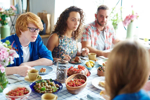 Young people sitting by Thanksgiving table — Stock Photo, Image