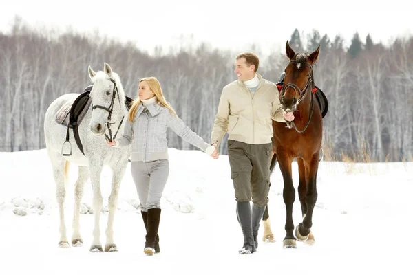 Pareja liderando sus caballos con riendas — Foto de Stock