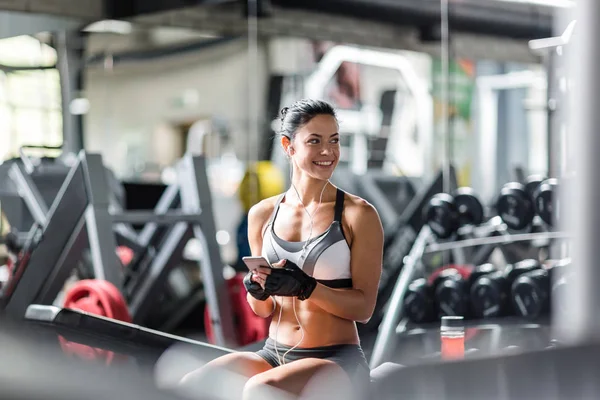 Mujer sonriente escuchando música en el gimnasio —  Fotos de Stock