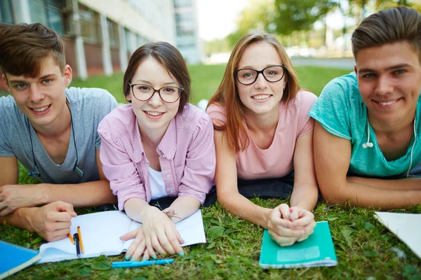 Students lying on campus lawn — Stock Photo, Image