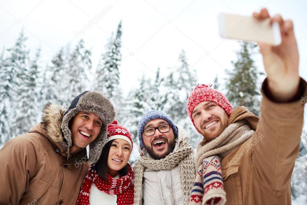 men and woman taking selfie in winter forest