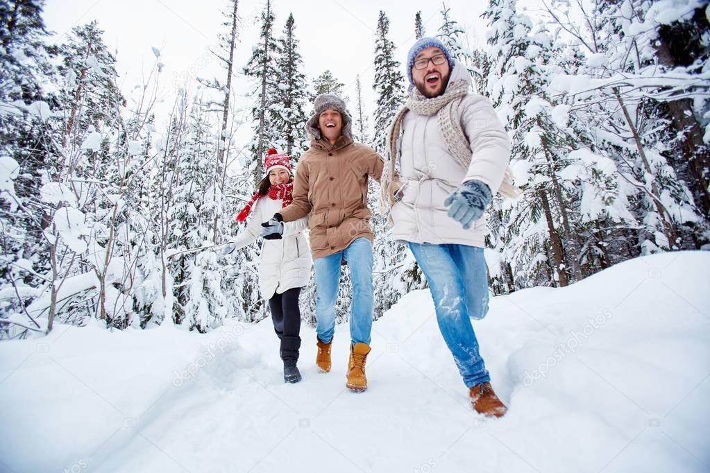 Happy friends running in winter forest 