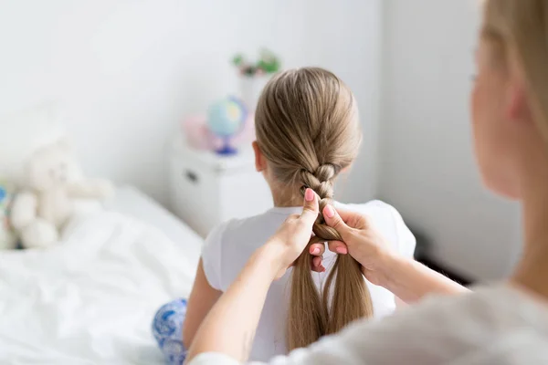 Kvinna flätning hennes dotter långt hår — Stockfoto