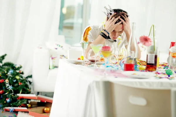 Hombre sentado en la mesa después de la fiesta turbulenta —  Fotos de Stock