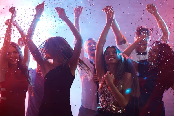 Extatisk vänner dansar i konfetti regn — Stockfoto