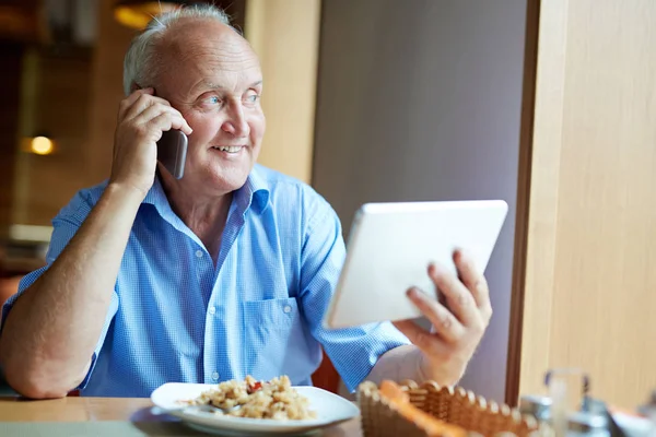 Moderner Rentner mit Touchpad, der auf dem Handy spricht — Stockfoto