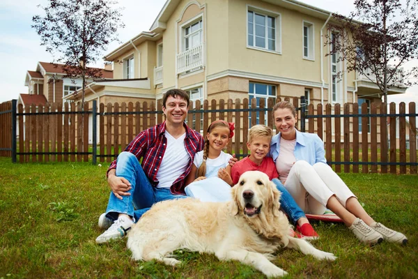 Famiglia seduta sull'erba con cane — Foto Stock