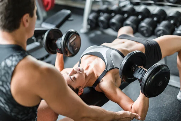 Woman with dumbbells exercising with trainer — Stock Photo, Image
