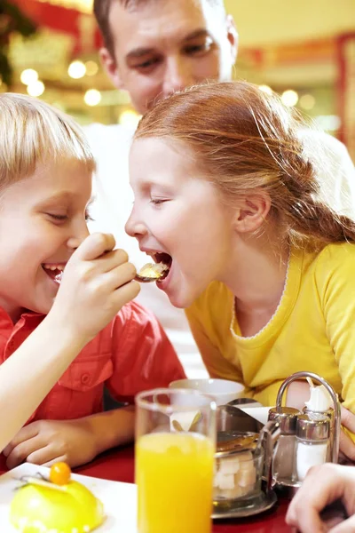 小男孩在咖啡馆里喂养他的妹妹 — 图库照片