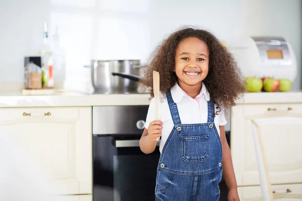 Kleines Mädchen mit Kochutensilien aus Holz — Stockfoto