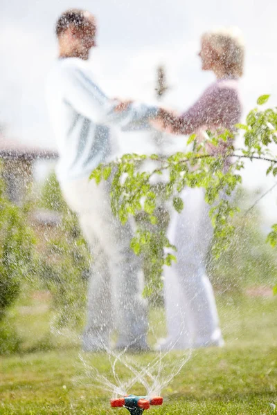 Lekfulla par genom sprinkler stänk — Stockfoto