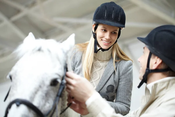 Kobieta siedzi na koniu i patrząc na instruktora — Zdjęcie stockowe