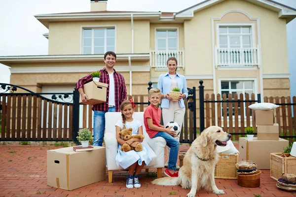 Geschwister sitzen bei gepackten Sachen mit Eltern im Hof — Stockfoto