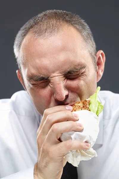 Голодный менеджер, кусающий бутерброд — стоковое фото