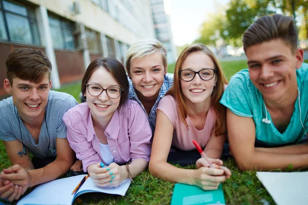 Friends lying on campus lawn — Stock Photo, Image