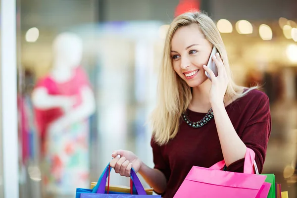 Woman talking on mobile phone after shopping — Stock Photo, Image