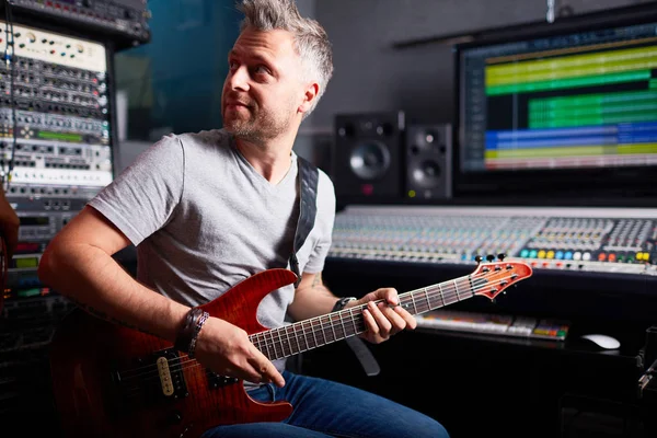 Музыкант играет на гитаре в студии звукозаписи — стоковое фото