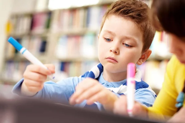 Chłopiec siedzi w szkole i rysunek — Zdjęcie stockowe