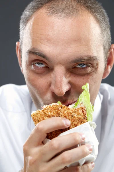 Голодный офисный работник, жующий сэндвич — стоковое фото