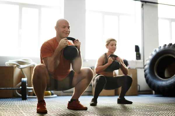 Homme et femme faisant de l'exercice avec des cloches bouilloire — Photo