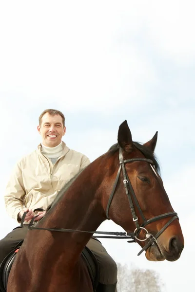 Schöner Mann, der draußen ein Pferd reitet — Stockfoto