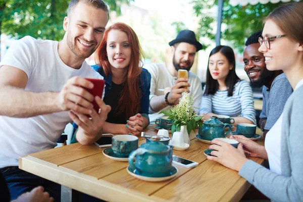 Uomo mostrando qualcosa ai suoi amici in smartphone — Foto Stock