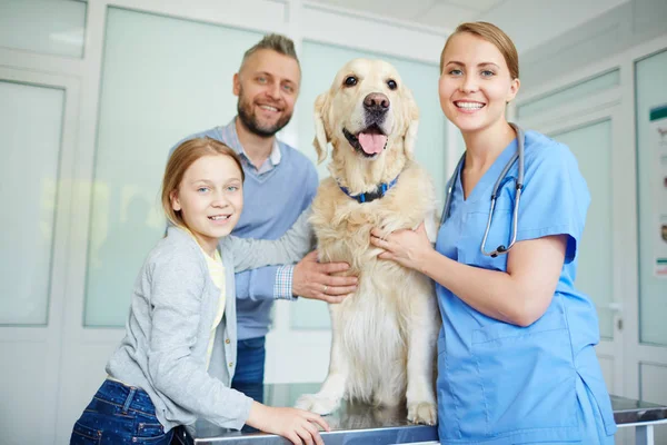 Freundlicher Tierarzt, Hund und seine Besitzer — Stockfoto