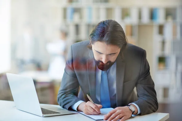 Jovem empresário fazendo anotações no escritório — Fotografia de Stock