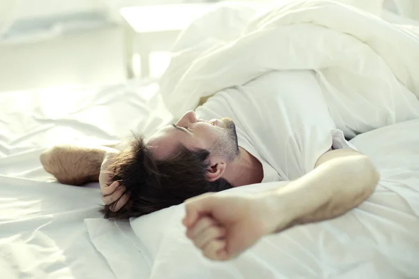 Człowiek luxuriating w łóżku — Zdjęcie stockowe