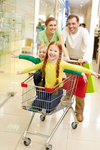 Rodziców, prowadzenie ich dzieci w koszyk na zakupy — Zdjęcie stockowe
