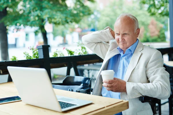 Zamyślony człowiek starszy patrząc na laptopa — Zdjęcie stockowe