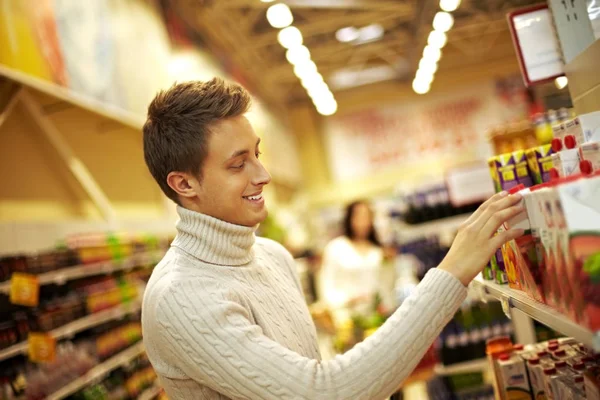 Мужчина выбирает сок в супермаркете — стоковое фото