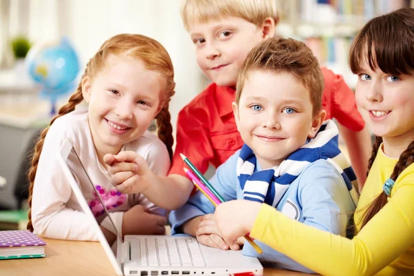 Escolares sentados em sala de aula com laptop — Fotografia de Stock