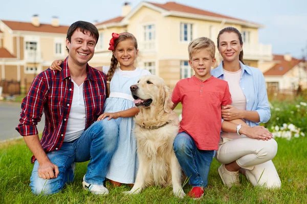 Glückliche Familie mit Hund schaut in die Kamera lizenzfreie Stockfotos