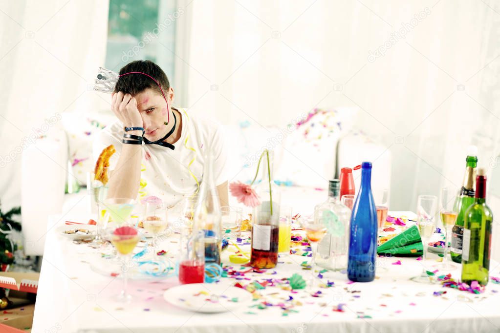 man sitting at messy table after party