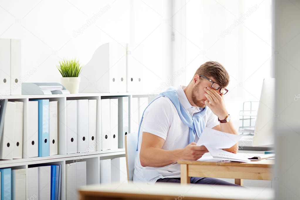 Tired accountant sitting at workplace 