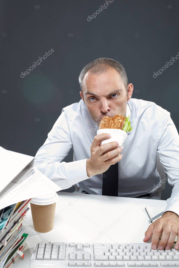 Manager chewing sandwich while working 
