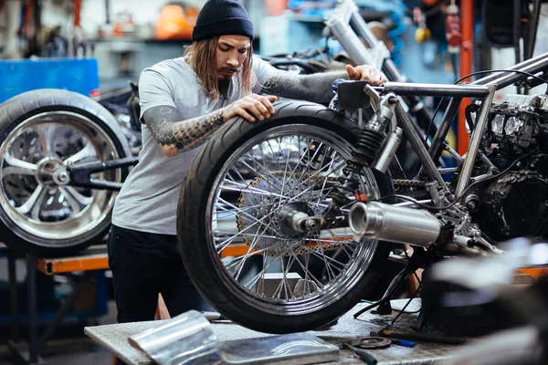 Hipster repareren wiel van motorfiets — Stockfoto