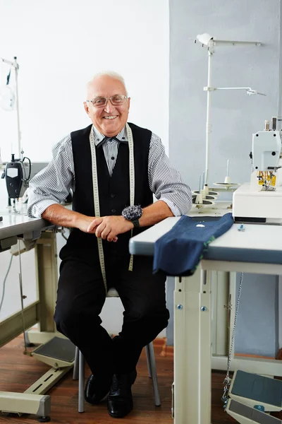 Sastre sonriente sentado en el taller — Foto de Stock