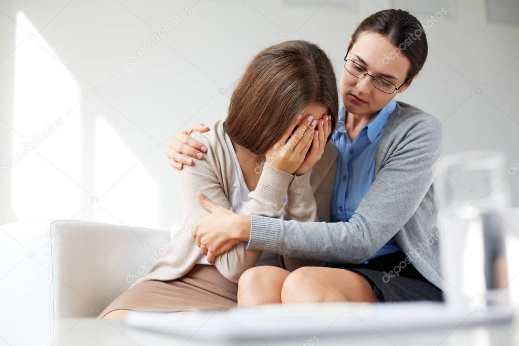 girl weeping while psychologist embracing her