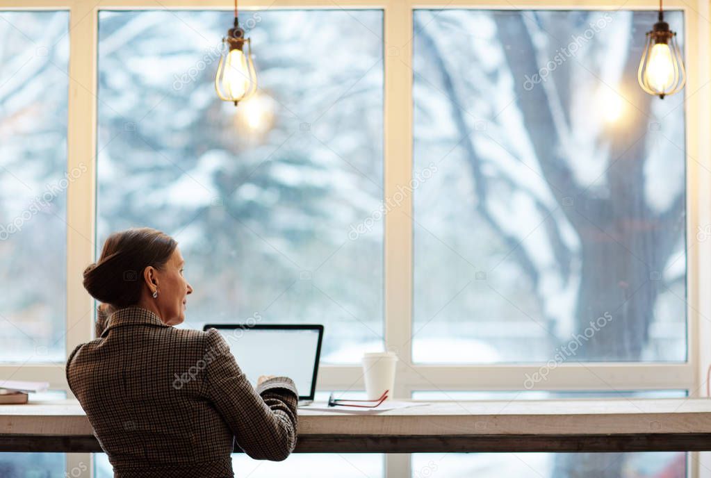 Businesswoman with laptop looking through window 