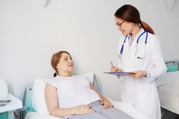 Médecin prescrivant la recette à sa patiente enceinte — Photo