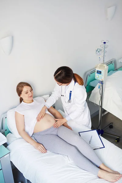 Mujer embarazada y médico tocándose el estómago — Foto de Stock