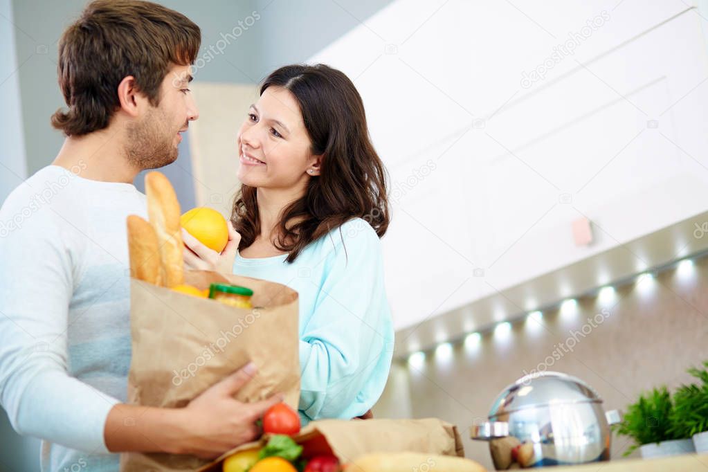 Couple with packet of food in the kitchen