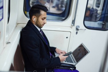 Dizüstü bilgisayar ile metro içinde oturan adam  