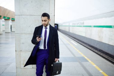 İstasyonda duran ve smartphone kullanarak adam